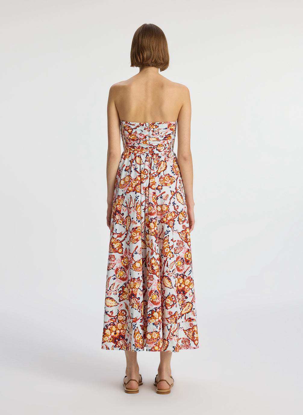 back view of woman wearing multicolor printed strapless midi dress