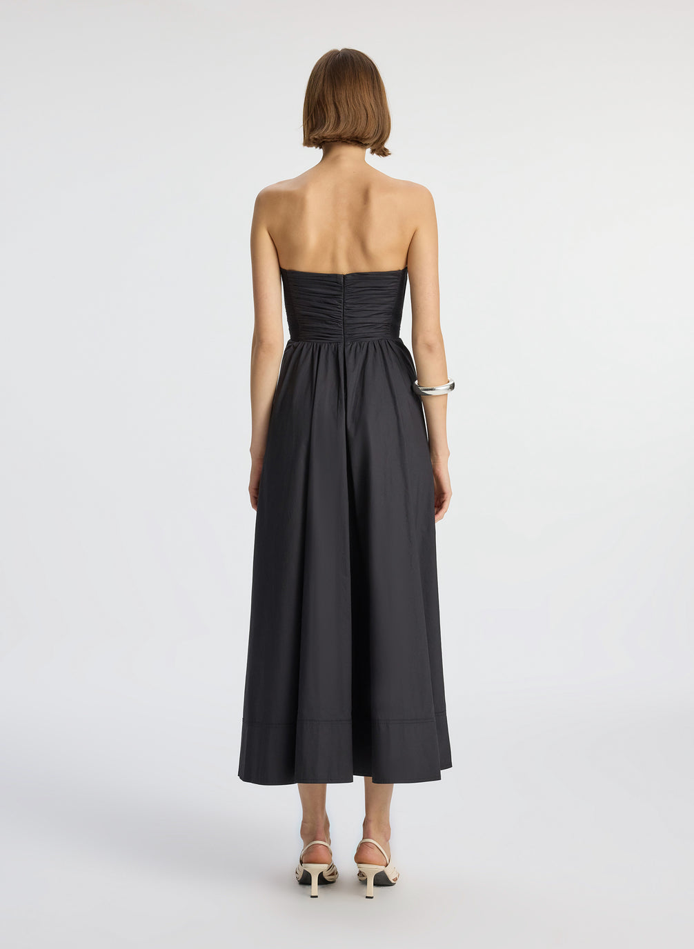 back view of woman wearing black strapless midi dress