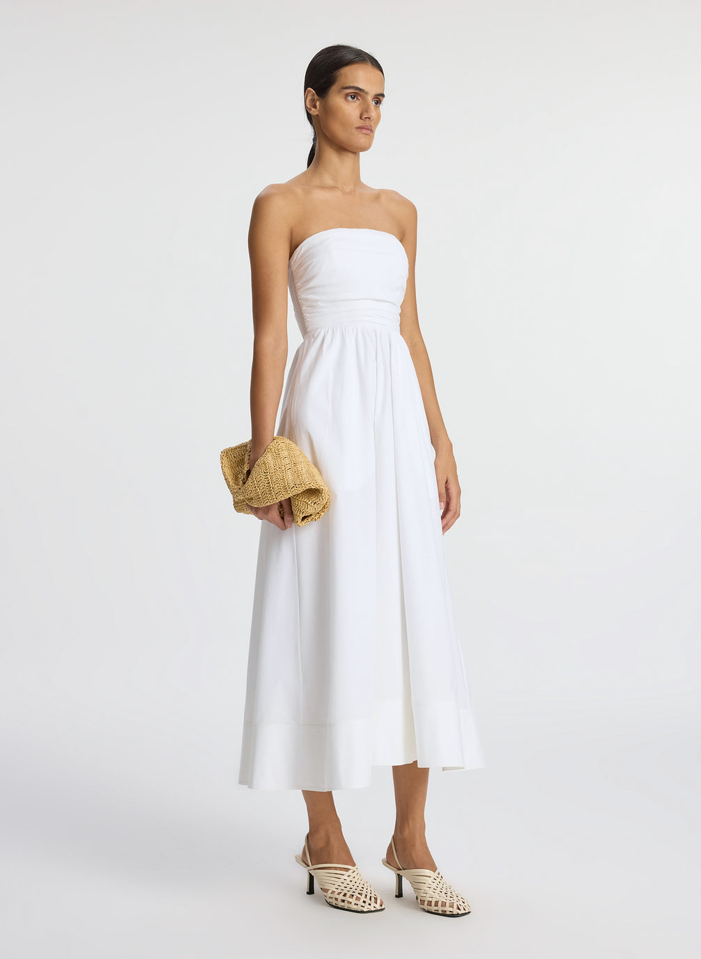 side view of woman wearing white strapless midi dress
