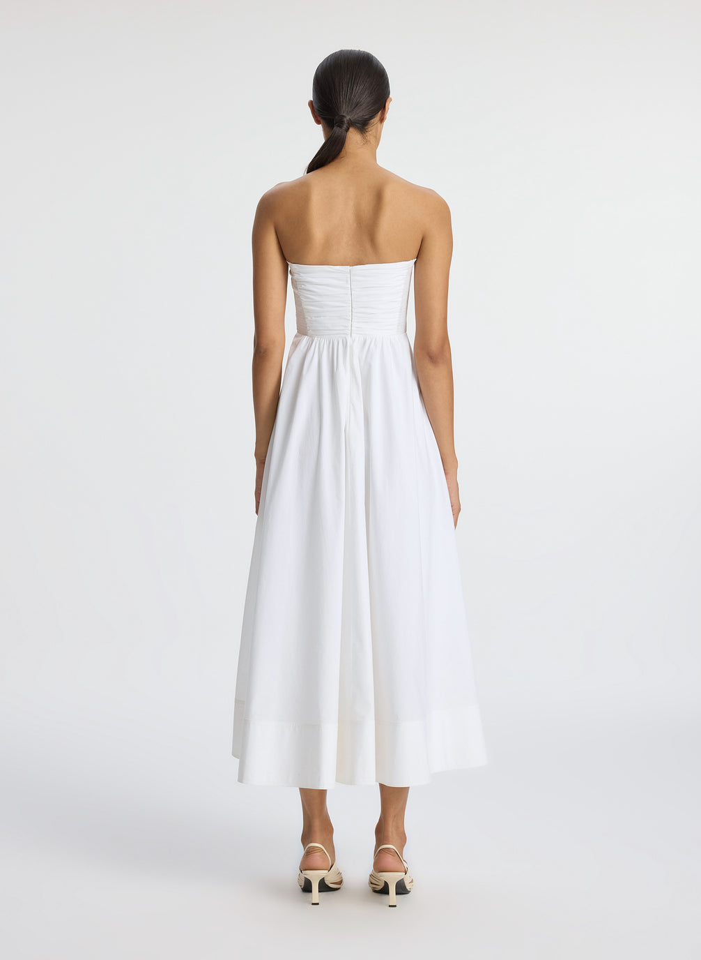back view of woman wearing white strapless midi dress