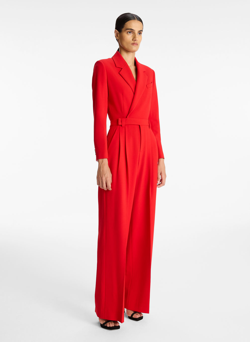 side view of woman wearing red long sleeve jumpsuit with back cutout