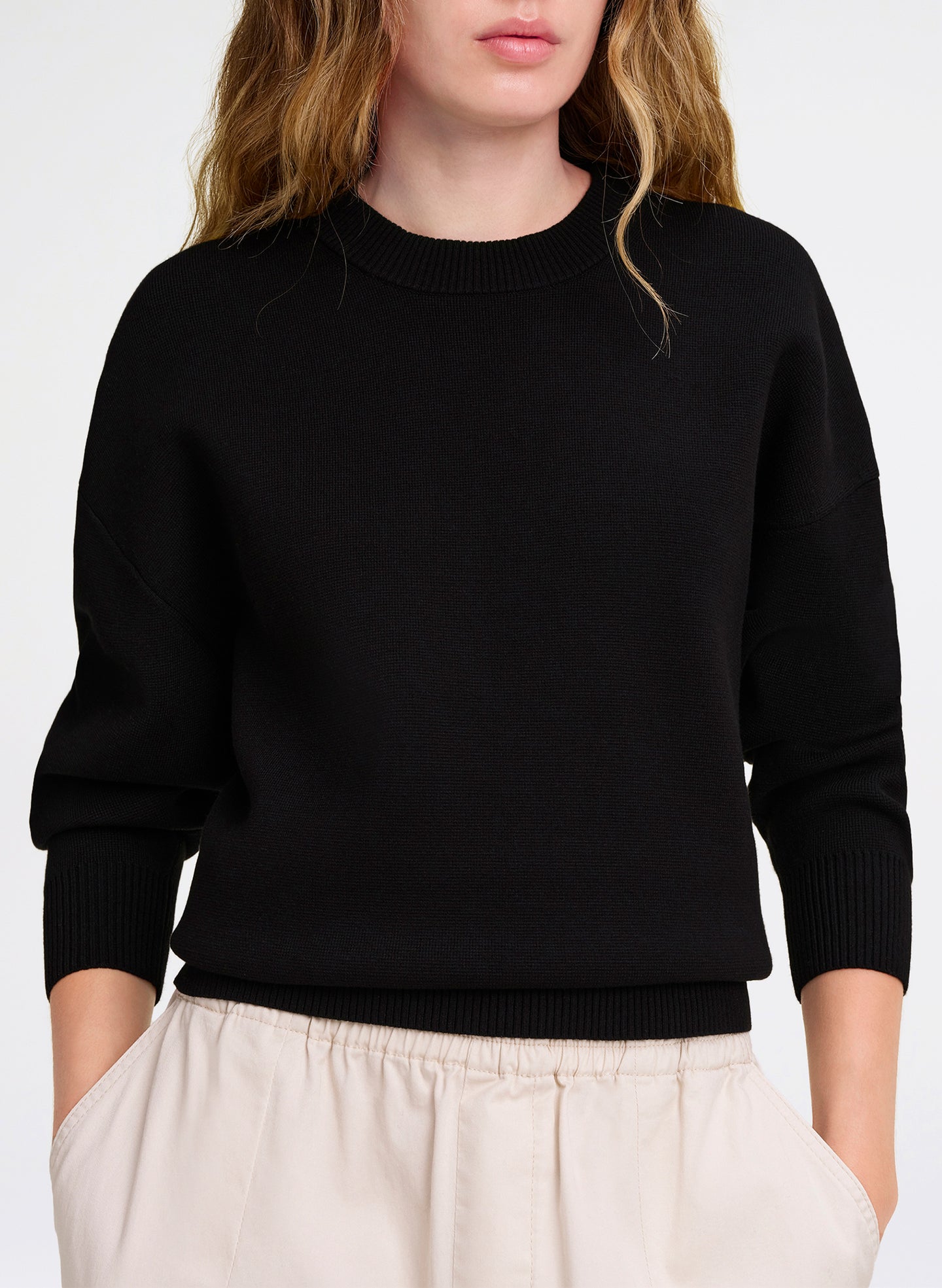 Person wearing a black sweater with a plain background