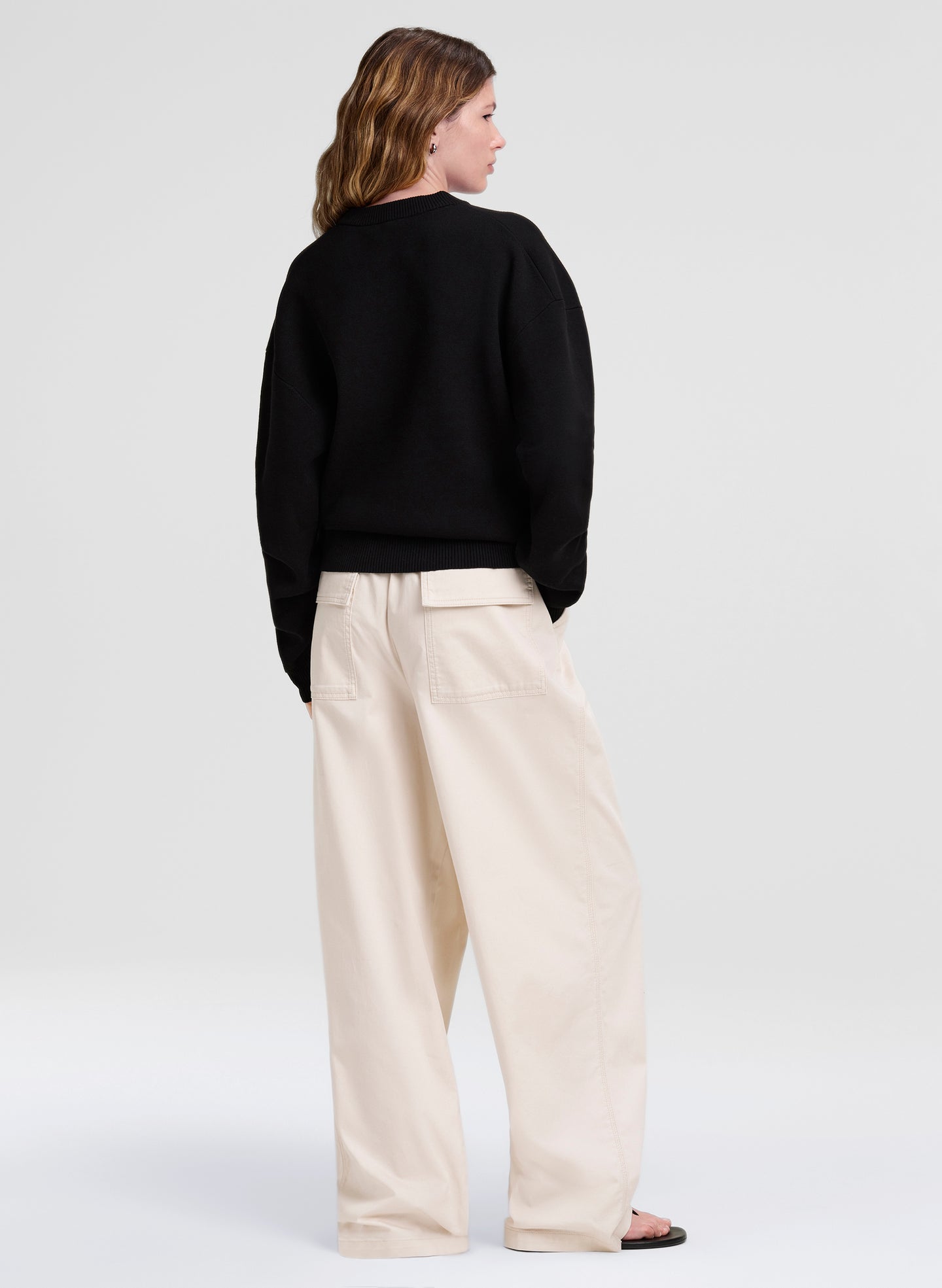 woman wearing a black sweater with cream pants