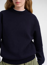 Person wearing a navy blue sweater on a white background
