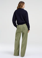 Person wearing a navy sweater and green pants on a white background