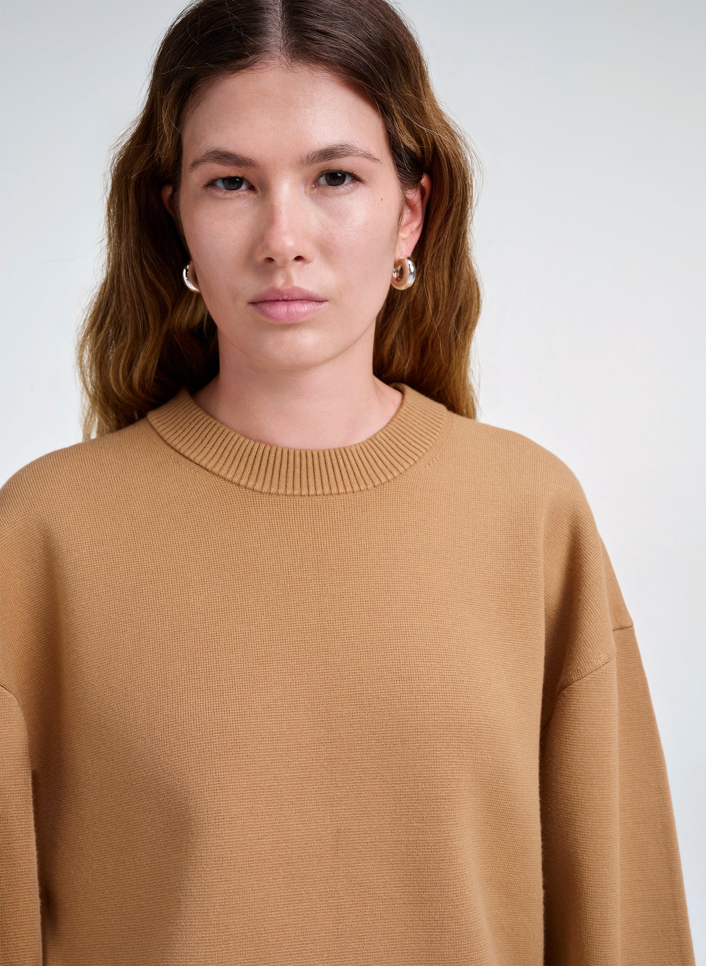 Woman wearing a brown sweater against a white background