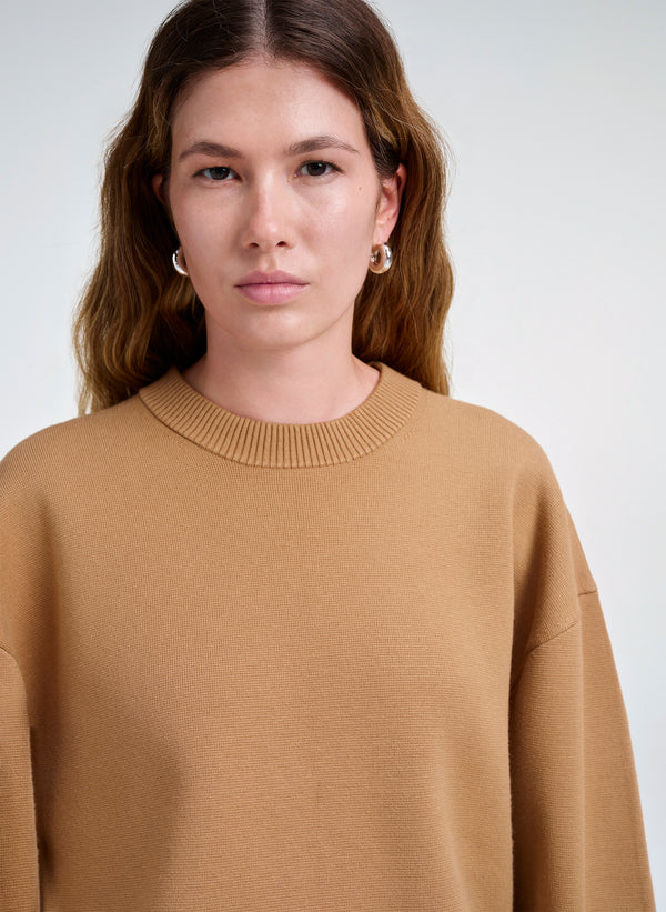 Woman wearing a brown sweater against a white background
