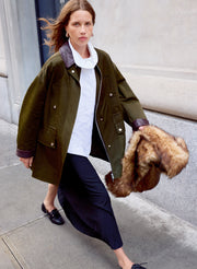 woman wearing white top, black skirt, and green jacket
