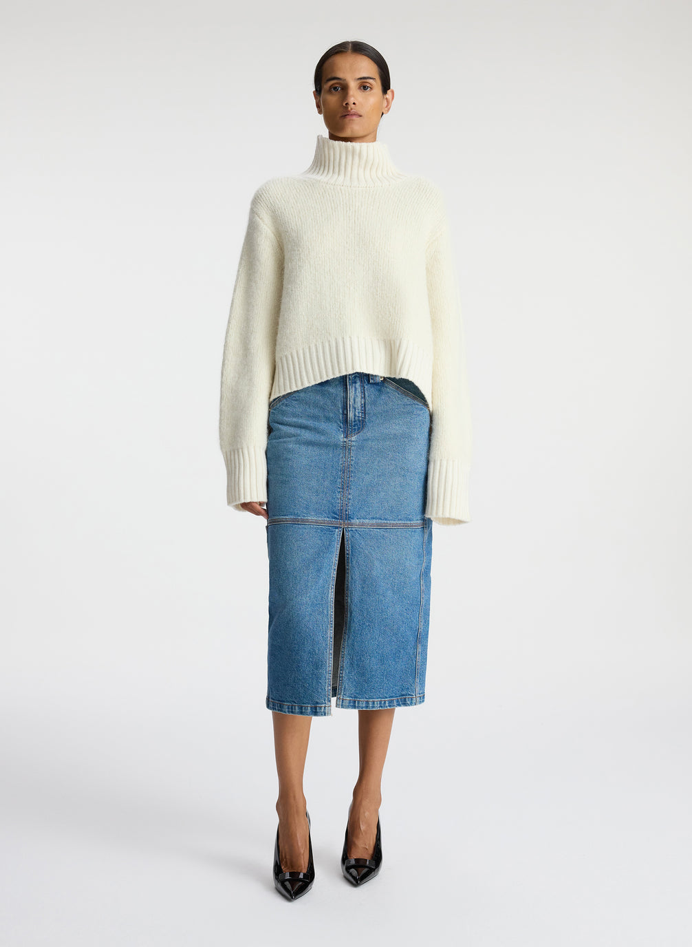 front view of woman wearing white turtleneck sweater and denim midi skirt