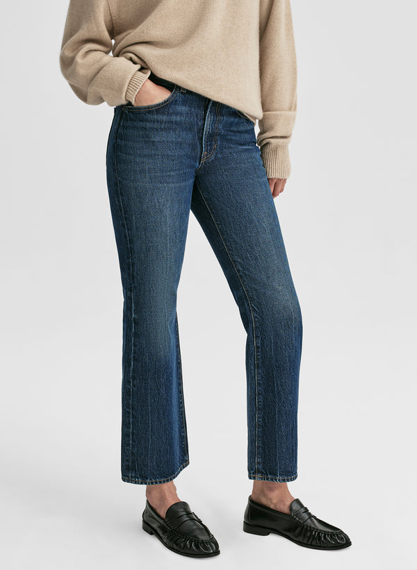 Person wearing blue jeans and a beige sweater on a white background