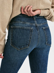 Person wearing blue jeans with a beige sweater on a white background