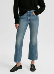 Person wearing blue jeans and black shoes on a white background