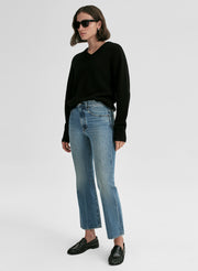 Person wearing a black sweater and blue jeans on a white background