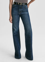 Woman wearing a grey sleeveless top and blue jeans on a white background