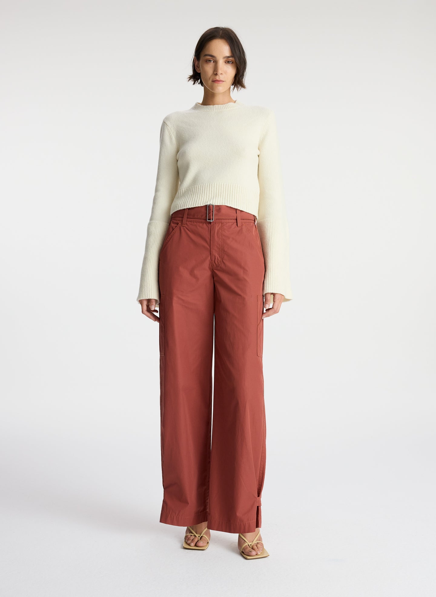 front view of a woman wearing a cream sweater and brown pants