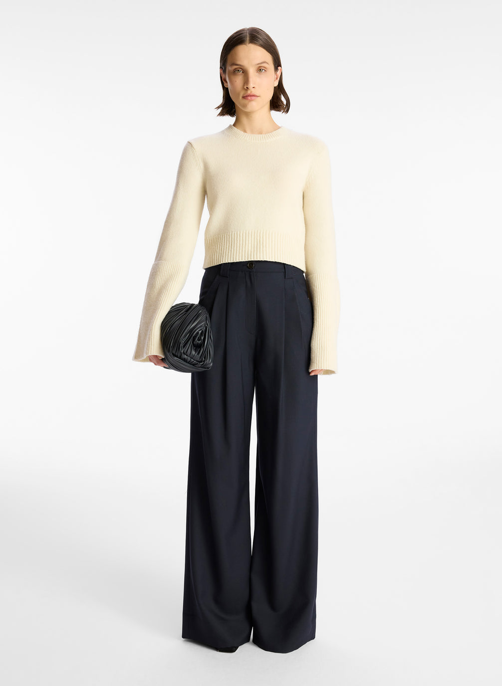 front view of a woman wearing a cream sweater and navy wide leg pants