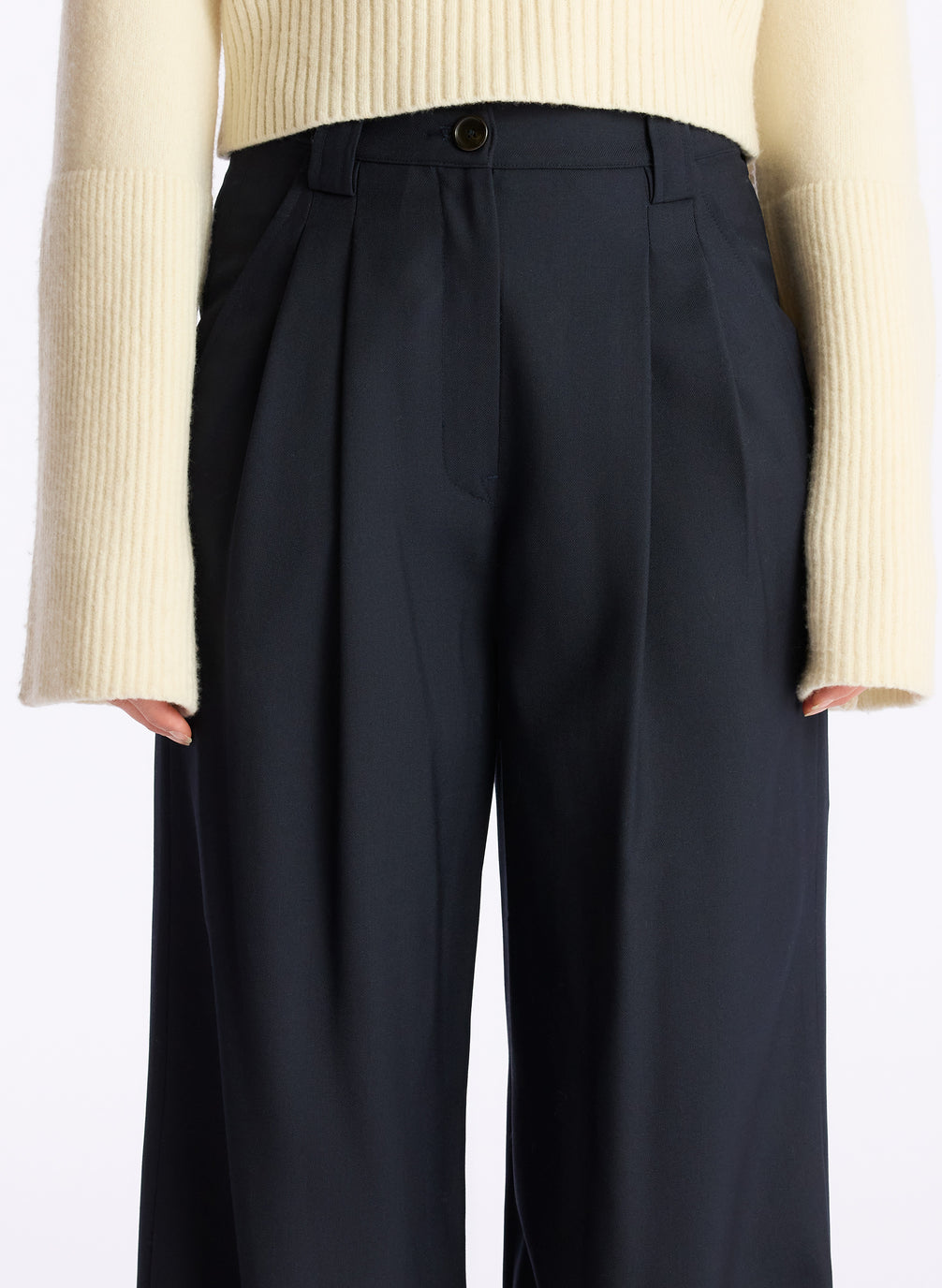 detail  view of a woman wearing a cream sweater and navy wide leg pants