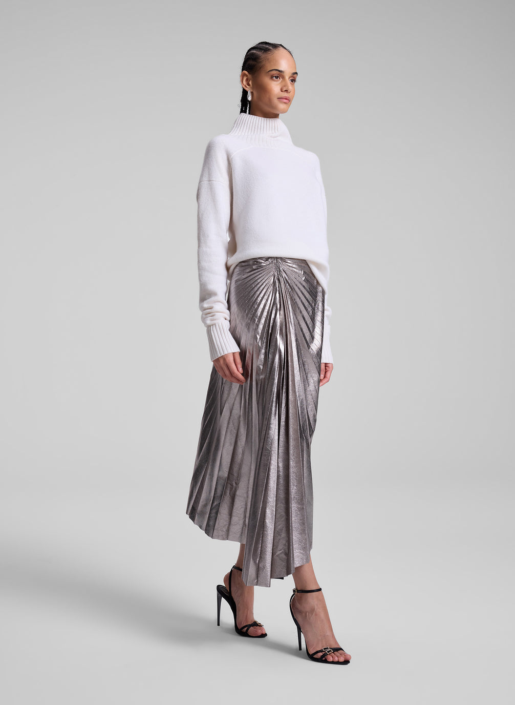 woman wearing white turtleneck sweater and grey metallic pleated skirt