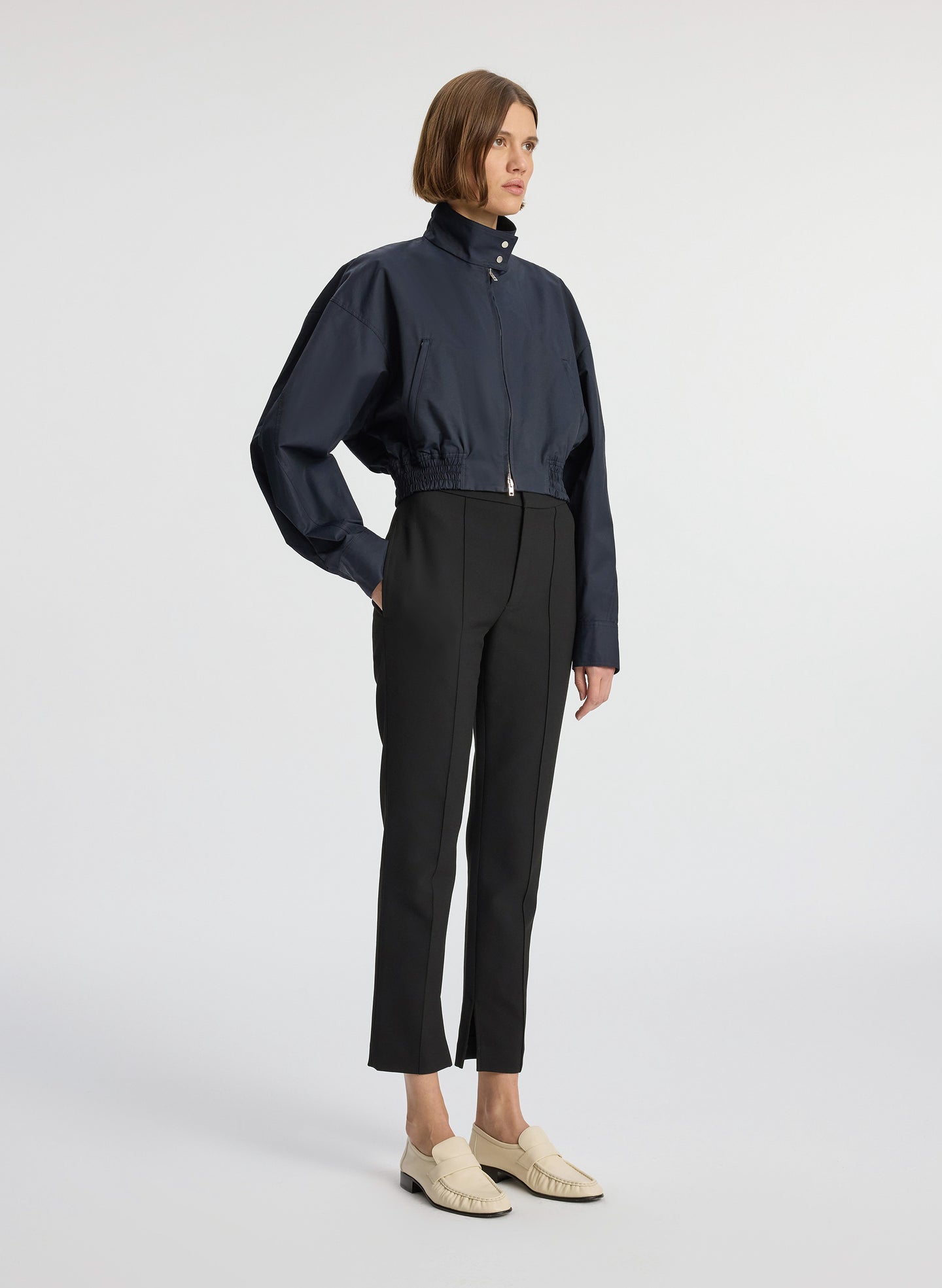 side view of woman in navy blue jacket and black ankle pants