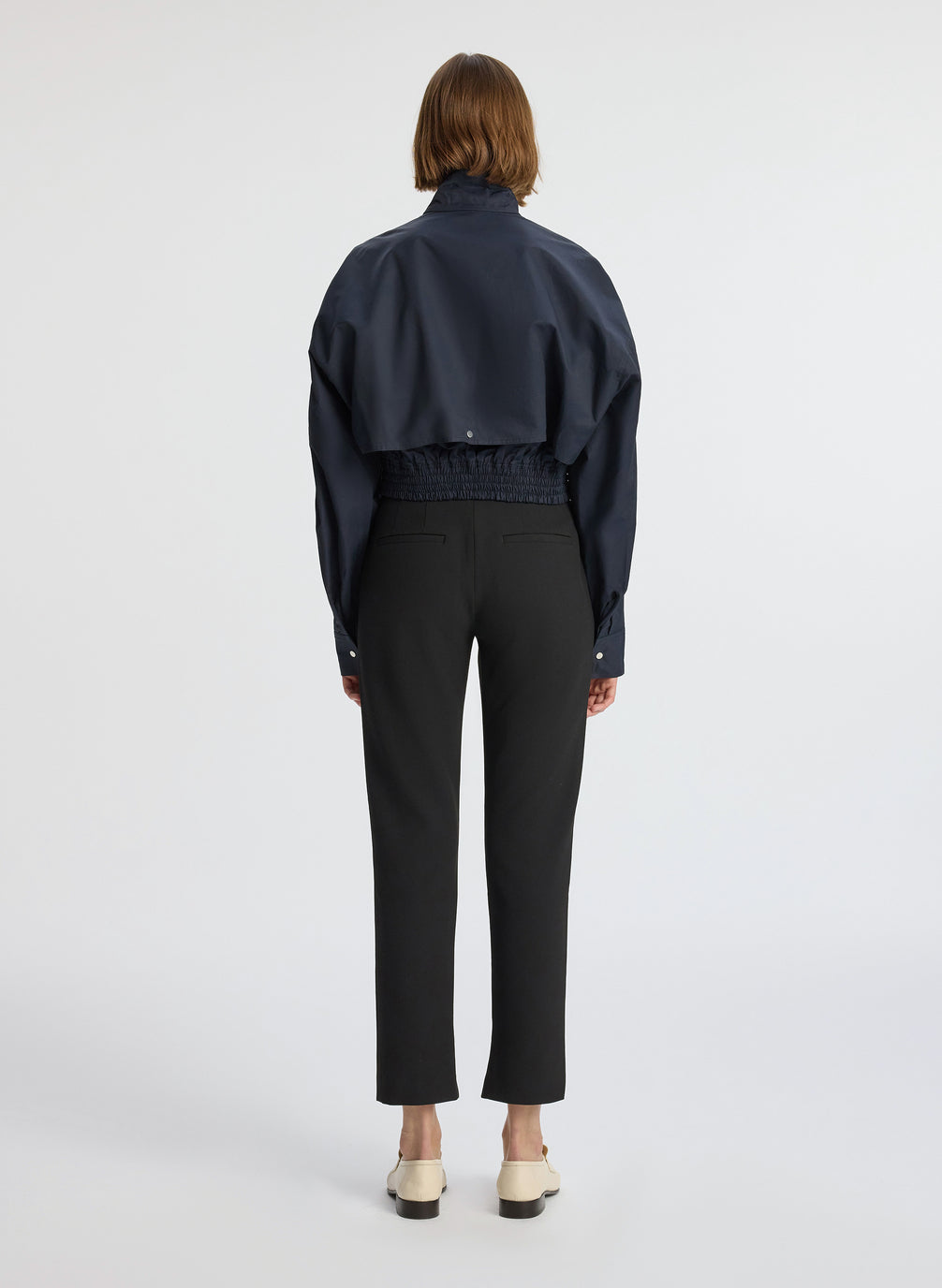 back  view of woman in navy blue jacket and black ankle pants