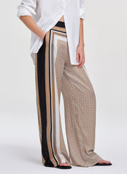 Person wearing a white shirt and patterned pants with stripes on a white background