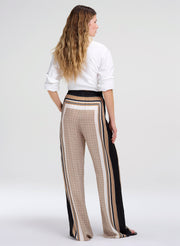 Woman wearing a white blouse and patterned pants on a white background