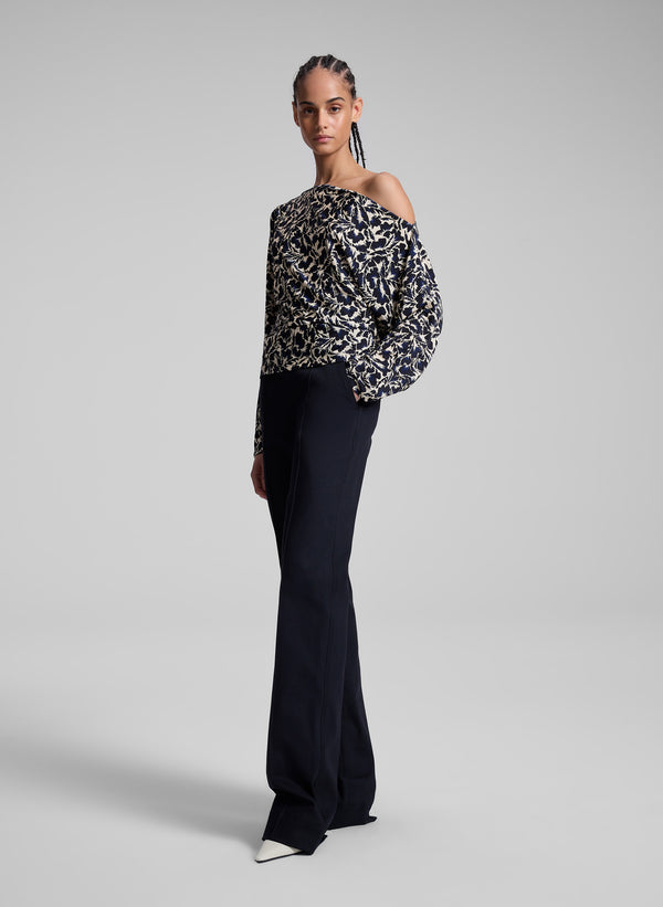 woman wearing patterned off one shoulder top with navy blue pants