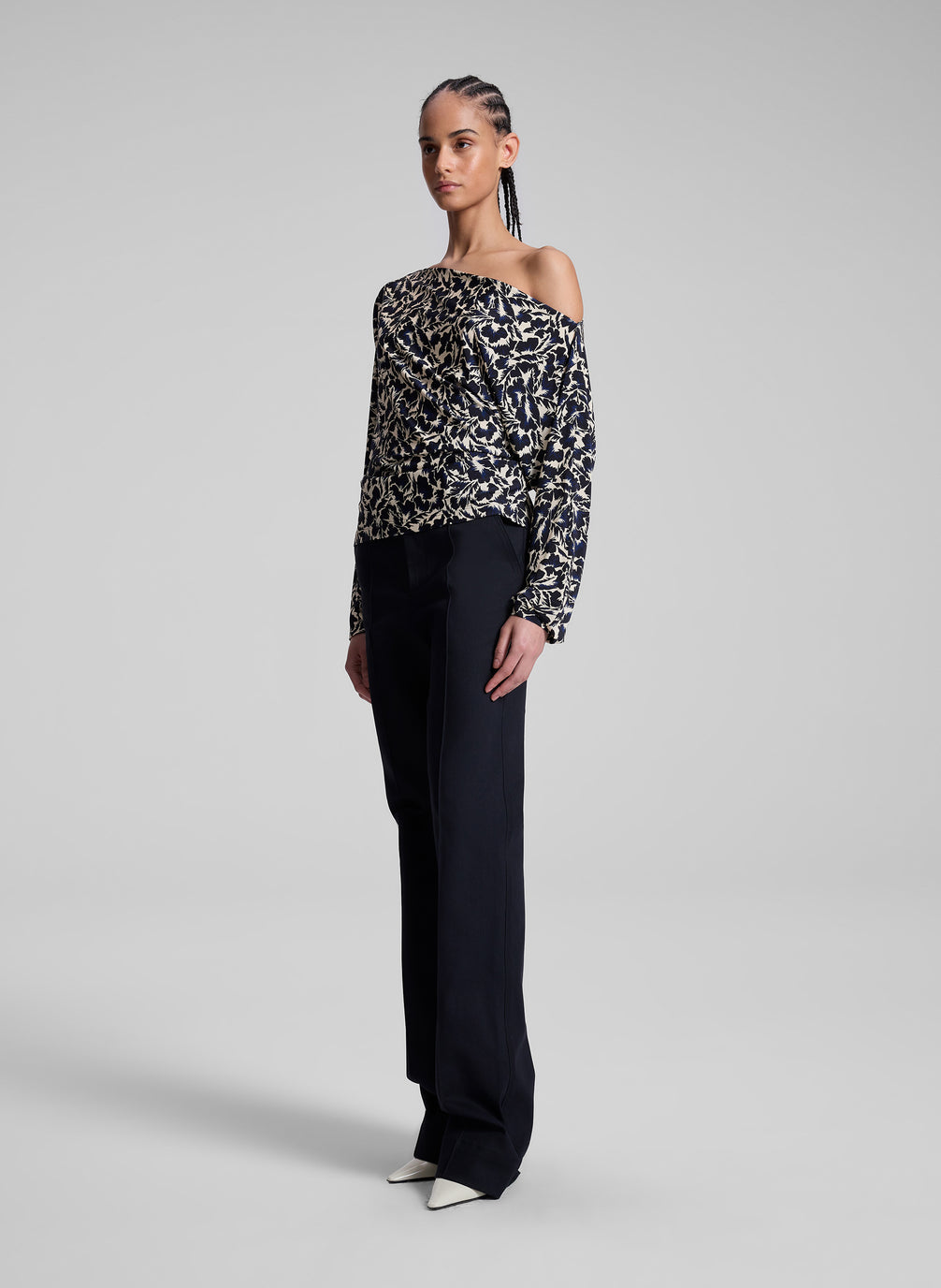 woman wearing patterned off one shoulder top with navy blue pants