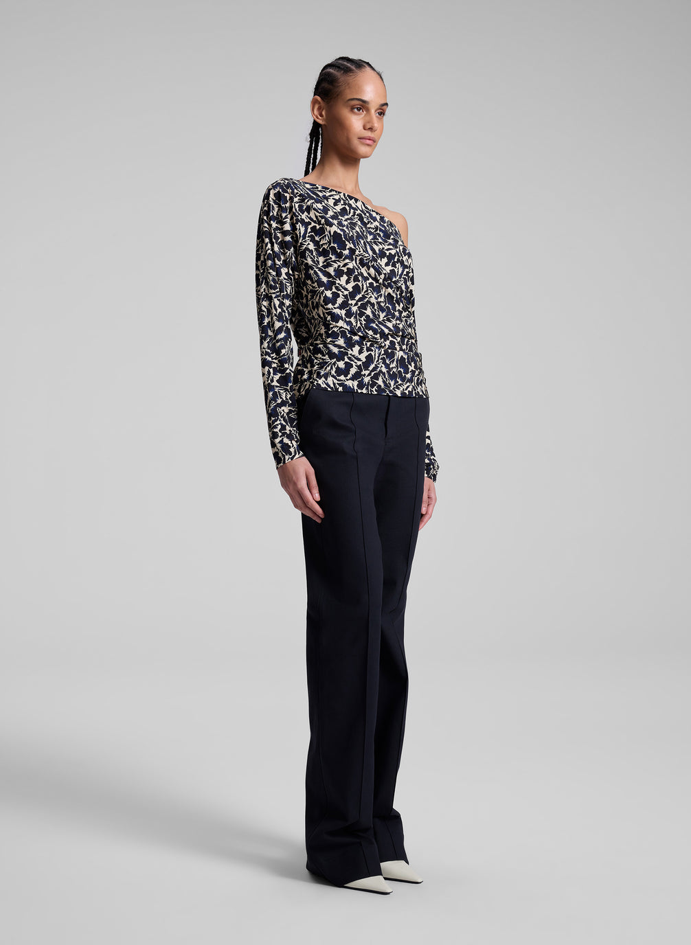 woman wearing patterned off one shoulder top with navy blue pants