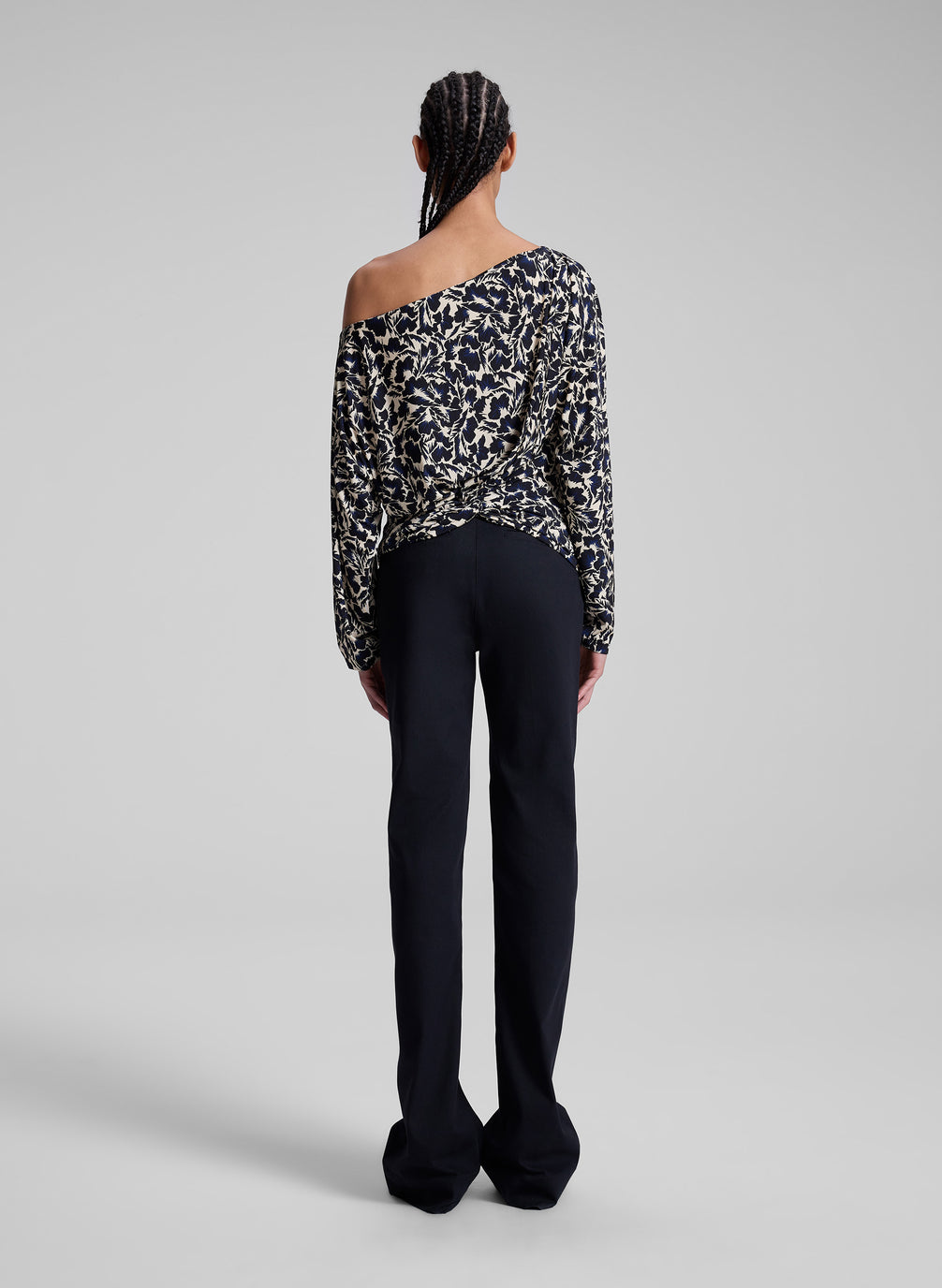 woman wearing patterned off one shoulder top with navy blue pants