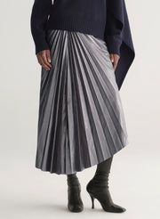 Person wearing a pleated skirt with a plain background
