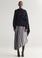 Person wearing a navy sweater and pleated skirt on a white background