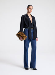 woman wearing black top and blue jeans carrying faux fur handbag
