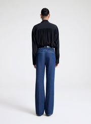 Person wearing a black shirt and blue jeans on a white background