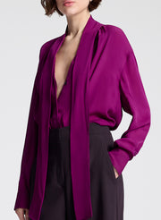 Woman wearing a purple blouse and dark purple pants on a white background