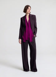 Woman wearing a purple blouse and dark purple pants on a white background