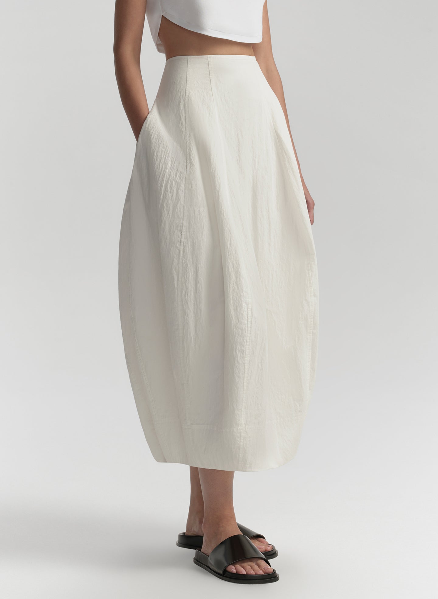 Person wearing a white skirt and white top on a light gray background