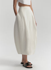 Person wearing a white skirt and white top on a light gray background