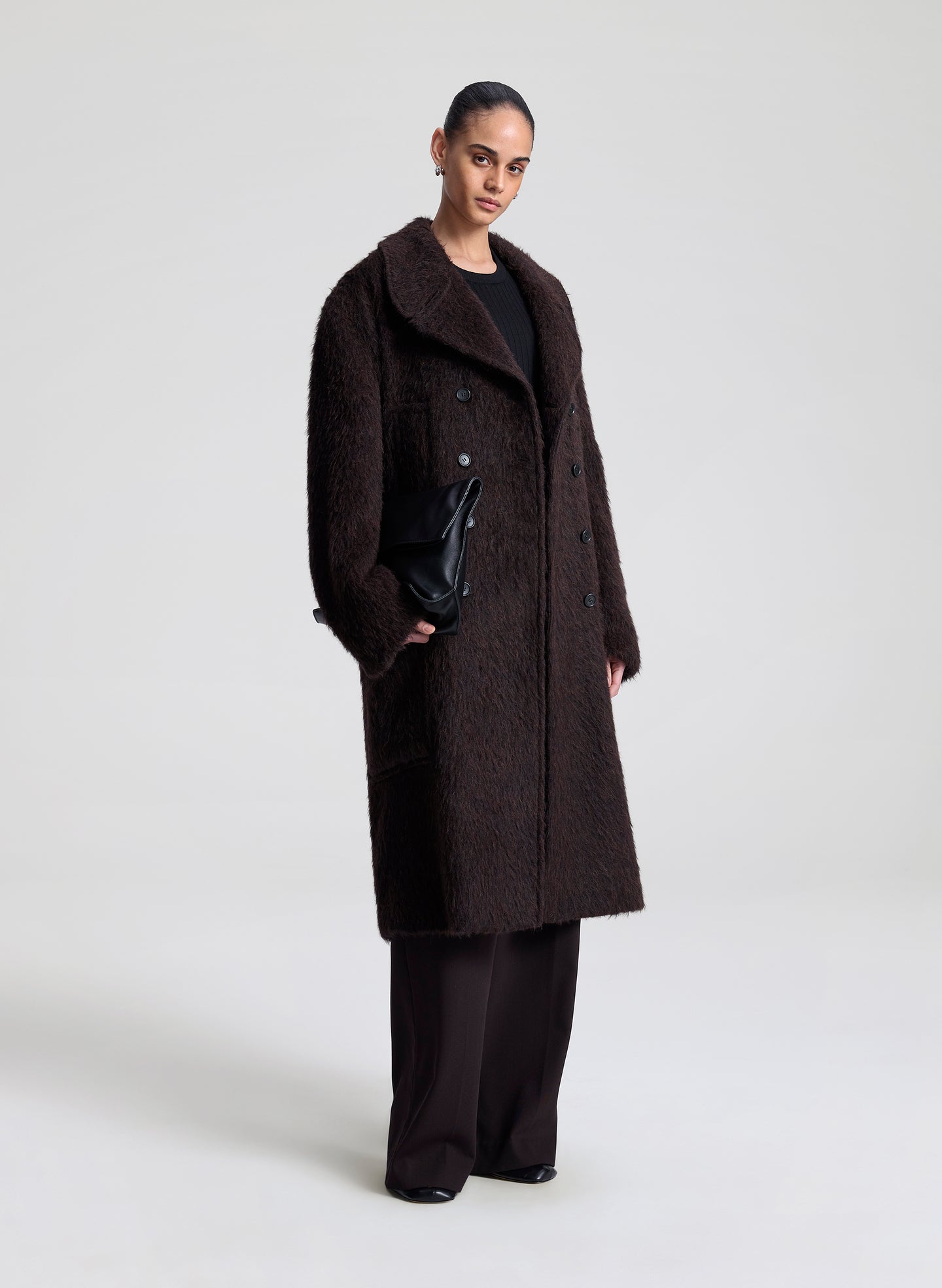 Person wearing a dark brown coat on a white background