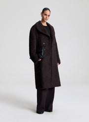 Person wearing a dark brown coat on a white background