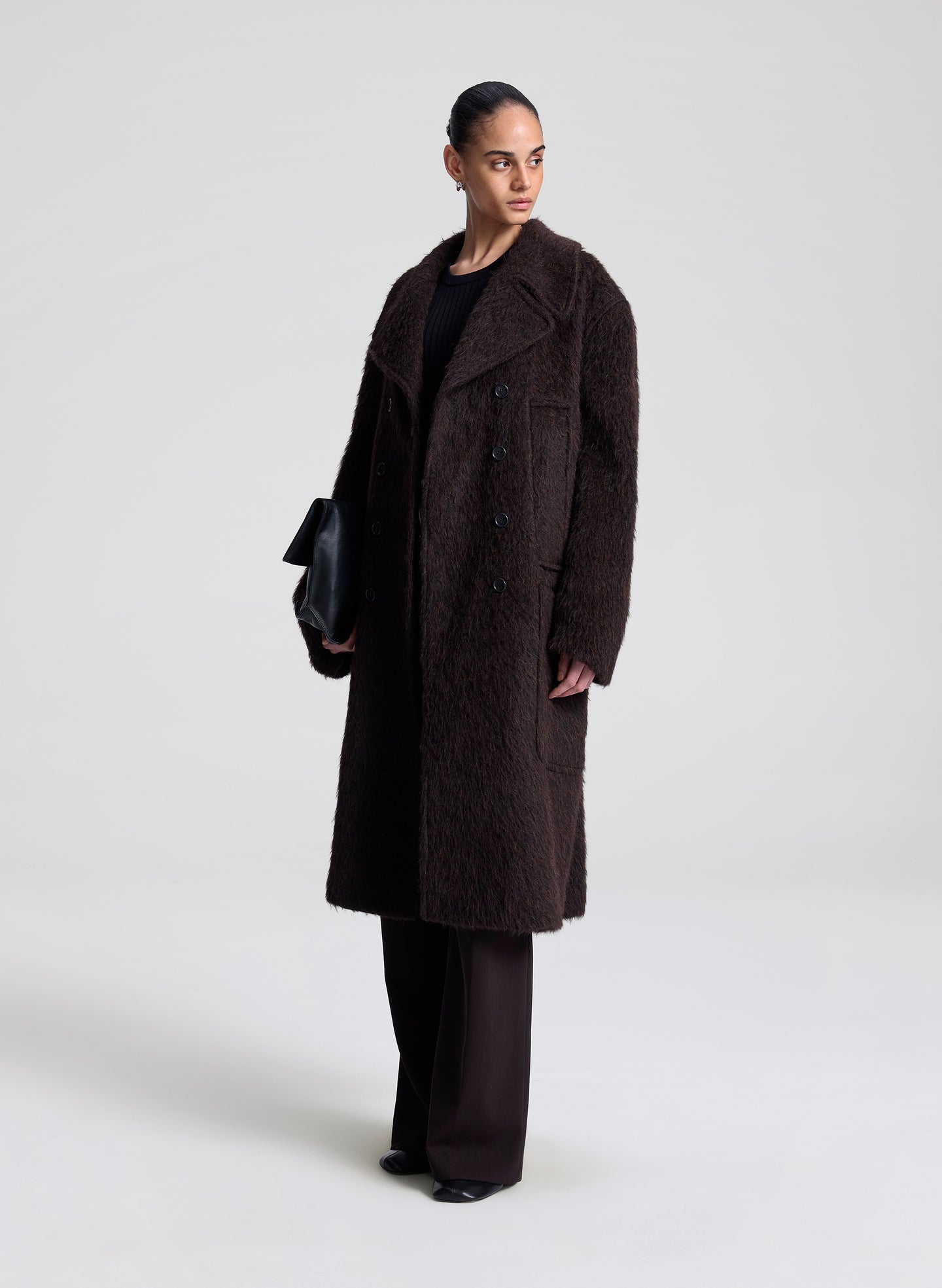 Person wearing a dark brown coat on a white background