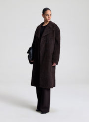 Person wearing a dark brown coat on a white background