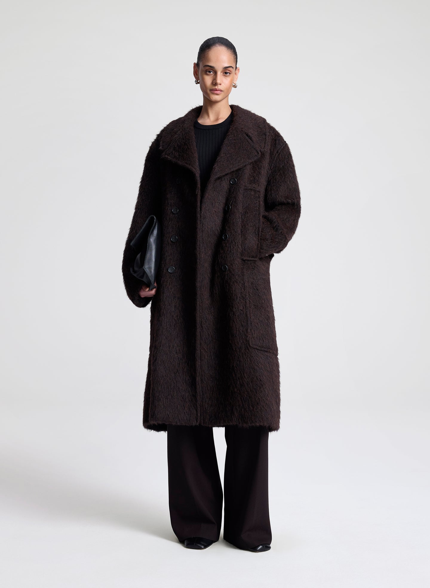 Person wearing a dark brown coat on a white background