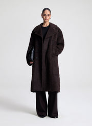 Person wearing a dark brown coat on a white background