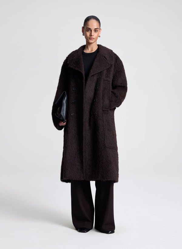 Person wearing a dark brown coat on a white background