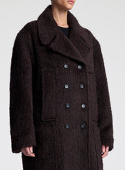 Person wearing a dark brown coat on a white background