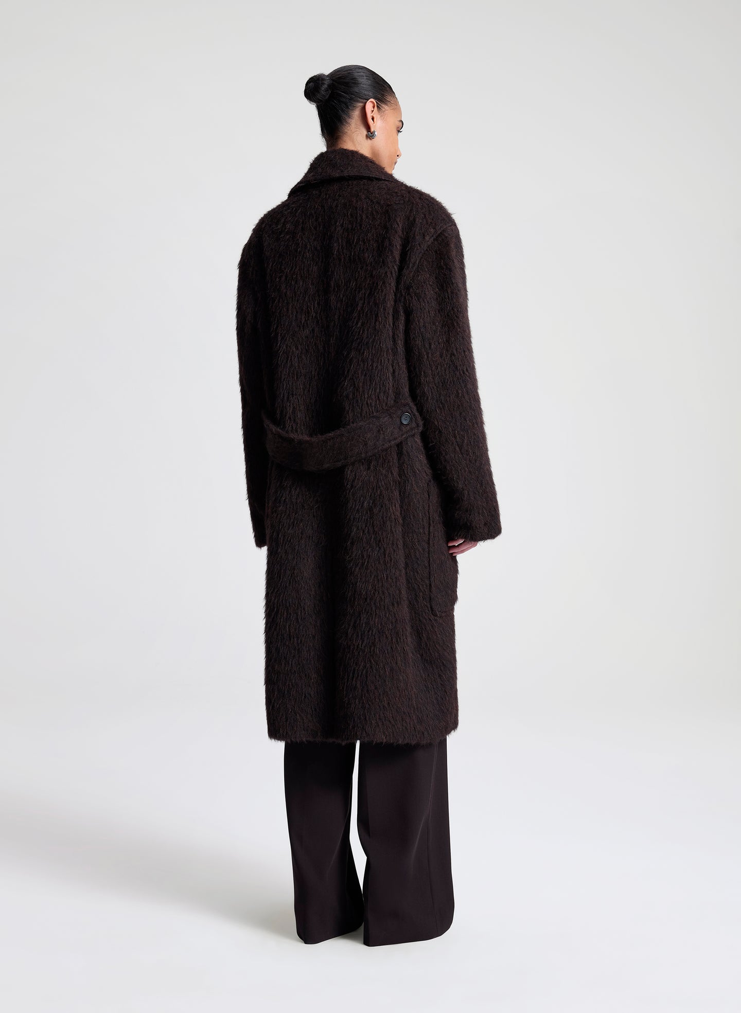 Person wearing a dark brown coat on a white background