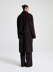 Person wearing a dark brown coat on a white background