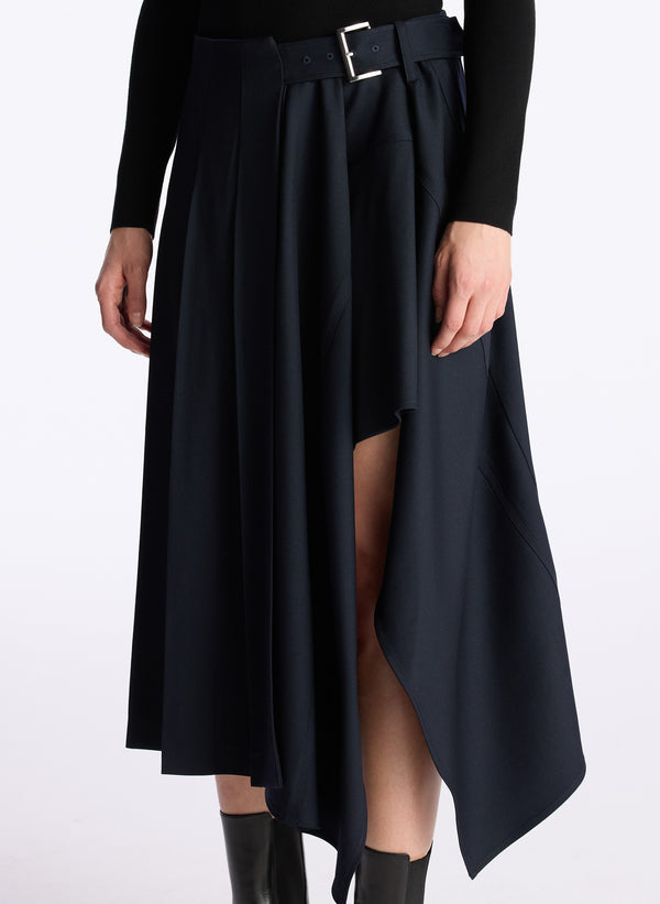 detail view of woman in black long sleeve knit top and navy blue pleated skirt