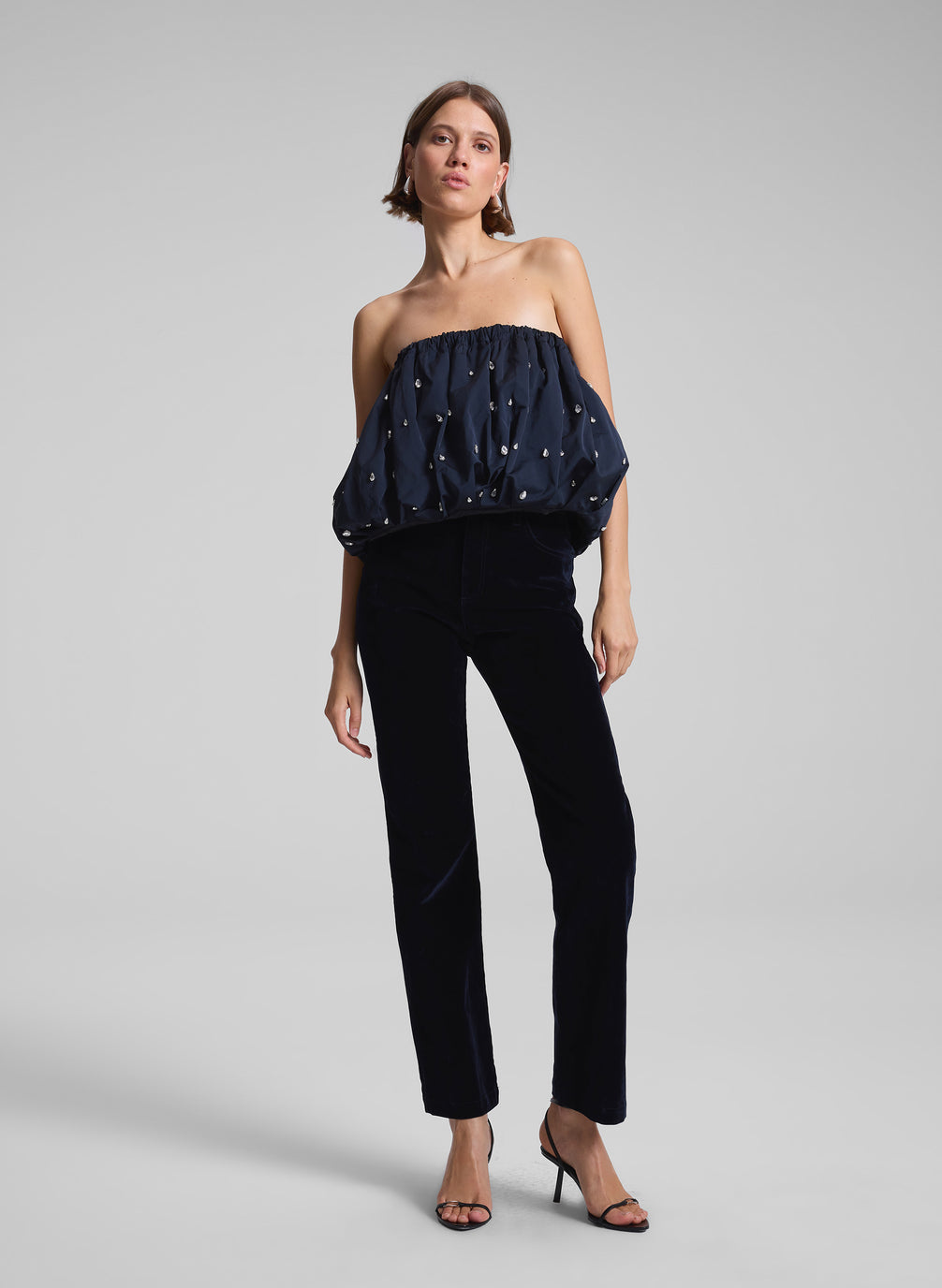 woman wearing navy embellished strapless top and navy blue velvet pants